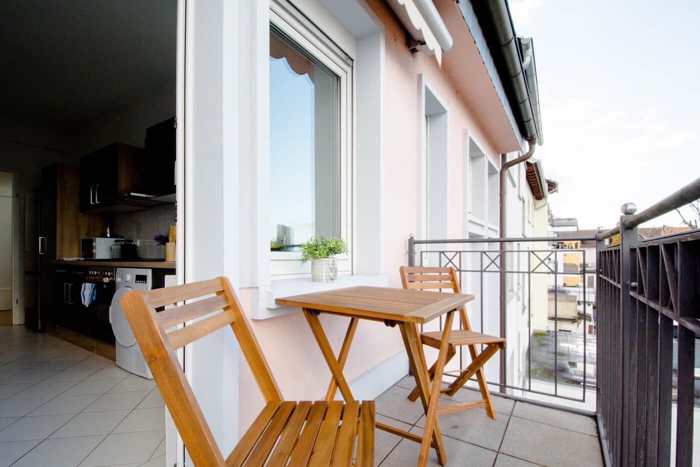 Balkon mit Holztisch und zwei Stühlen an einer von GLL vermieteten Wohnung